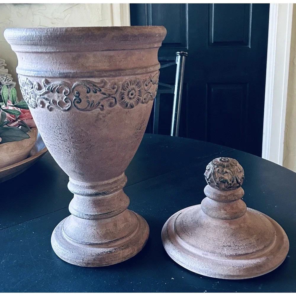 decorative terracotta urn with a distressed, rustic finish and a matching lid